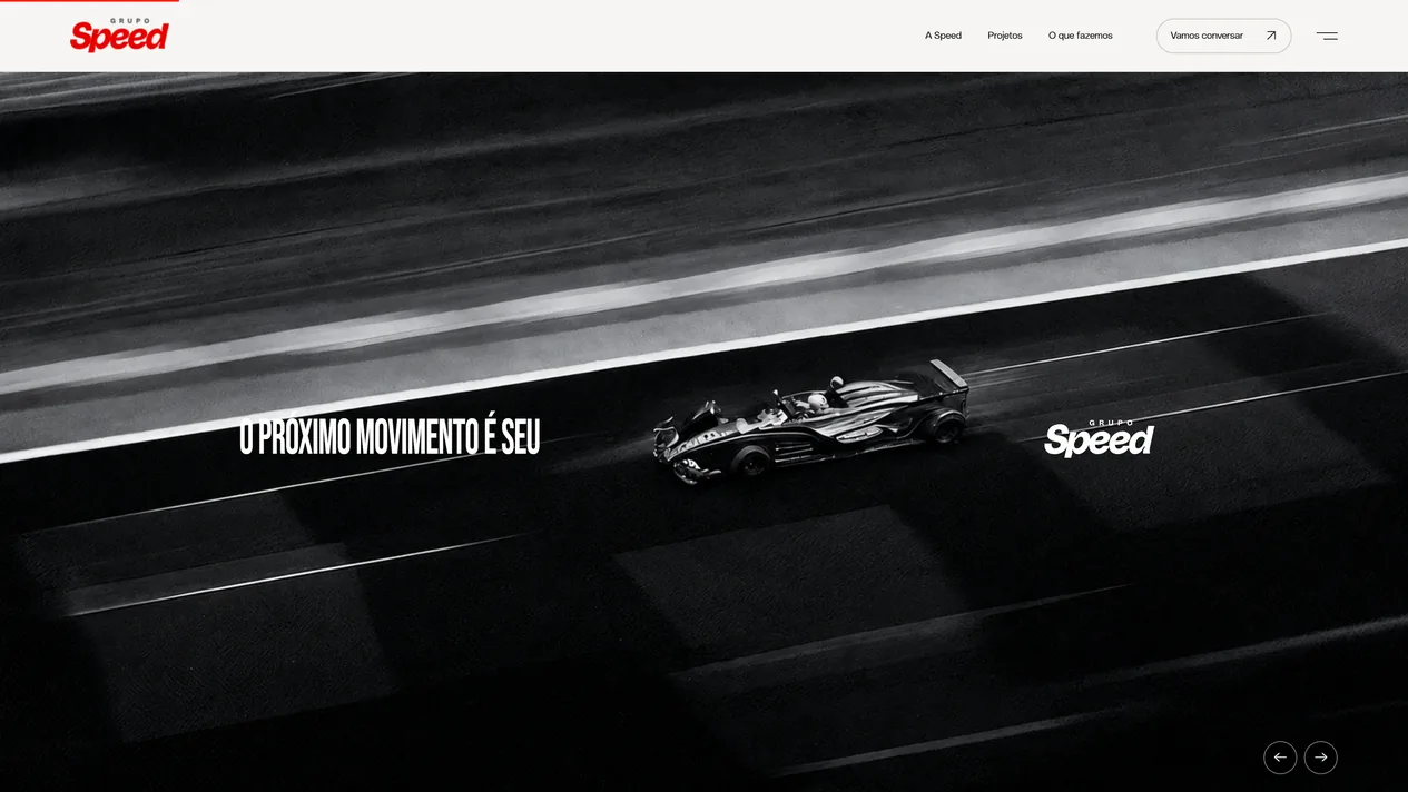 Segunda cena da abertura da home do Grupo Speed: foto em preto e branco de um carro de corrida na pista, com o título O próximo movimento é seu à esquerda, o logo branco à direita e duas setas de navegação no canto
